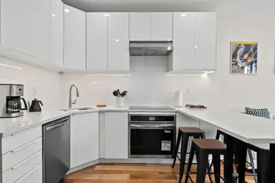 a kitchen with white cabinets and black appliances at Carroll Place - Bright 3BR Apt in Carroll Gardens in Brooklyn