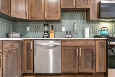 a kitchen with wooden cabinets and a stainless steel dishwasher at Modern Princeton Stay Steps from Nassau Street in Princeton