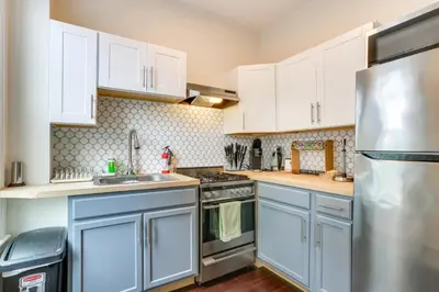 a kitchen with white cabinets and a stainless steel refrigerator at Explore and Work! Stylish Washington Heights Duplex in Newburgh