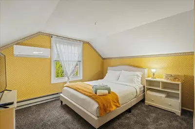 a bedroom with a bed with yellow walls and a window at InDoor HotTub Pocono Mountains Home