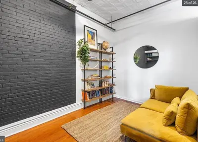 a living room with a yellow couch and a brick wall at Charming Retreat in Trendy NoLibs in Philadelphia