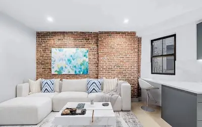 a living room with a couch and a brick wall at Duplex Dream 4-Bedroom Bonbon in New York