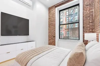 a bedroom with a bed and a flat screen tv at Duplex Dream 4-Bedroom Bonbon in New York