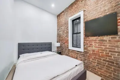 a bedroom with a bed and a brick wall at Duplex Dream 4-Bedroom Bonbon in New York