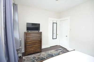 a bedroom with a tv on a dresser and a bed at Spacious Home with Parking, Laundry - Near RU, RWJ, NJ Transit in Highland Park