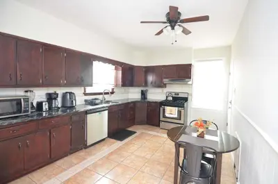 a kitchen with wooden cabinets and a ceiling fan at Spacious Home with Parking, Laundry - Near RU, RWJ, NJ Transit in Highland Park