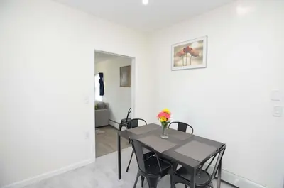 a dining room with a table with a vase of flowers on it at Cozy Beds with Parking, Laundry - Near RU, RWJ, NJ Transit in Highland Park
