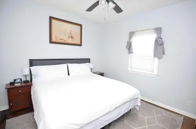 a white bedroom with a bed and a window at Spacious Home with Parking, Laundry - Near RU, RWJ, NJ Transit in Highland Park
