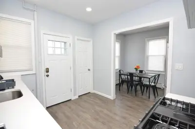 a kitchen and dining room with white walls and a table at Cozy Beds with Parking, Laundry - Near RU, RWJ, NJ Transit in Highland Park