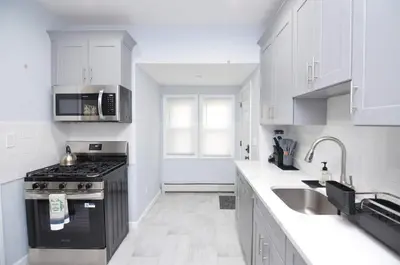 a white kitchen with a stove and a sink at Cozy Beds with Parking, Laundry - Near RU, RWJ, NJ Transit in Highland Park