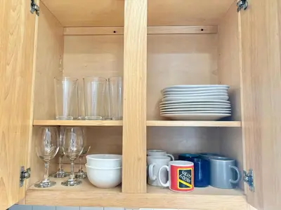 a wooden cabinet with glasses and plates and cups at FREE Parking near NYC Washer and Dryer in North Bergen