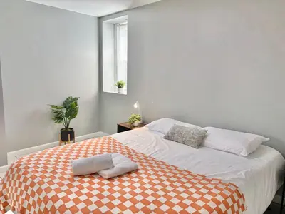 a bedroom with a bed with a orange and white blanket at FREE Parking near NYC Washer and Dryer in North Bergen