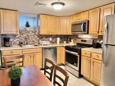 a kitchen with wooden cabinets and a table and a refrigerator at FREE Parking near NYC Washer and Dryer in North Bergen