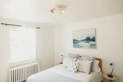 a bedroom with a bed with white sheets and pillows at Lady Grey Cottage - Hot Tub in Conestoga