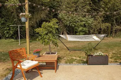 a hammock in a garden with a bench and a chair at Lady Grey Cottage - Hot Tub in Conestoga