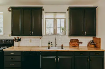 a kitchen with dark green cabinets and a sink at Conestoga Cottage with Hot Tub in Conestoga
