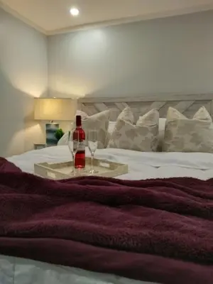 a bottle of wine sitting on top of a bed at So cute so cozy in Elizabeth