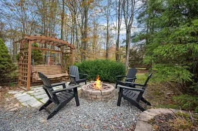a fire pit with two chairs and a wooden bench at Relaxing Pocono Stay Near Lake with Hot Tub & BBQ in Blakeslee