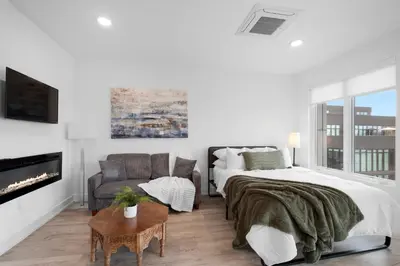 a white bedroom with a bed and a couch at Bright Studio Haven - Pool, Gym & Balcony Views in Philadelphia