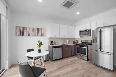 a kitchen with stainless steel appliances and a table and chairs at Bright Studio Haven - Pool, Gym & Balcony Views in Philadelphia