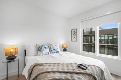a white bedroom with a bed and a window at Sleek 1BR Hideaway - Gym, Pool Balcony in Philadelphia