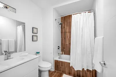 a white bathroom with a toilet and a sink at Sleek 1BR Hideaway - Gym, Pool Balcony in Philadelphia