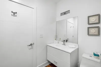 a white bathroom with a sink and a mirror at Sleek 1BR Hideaway - Gym, Pool Balcony in Philadelphia