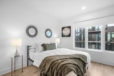 a white bedroom with a bed and two windows at Bright 1BR Haven - Balcony Skyline Views in Philadelphia