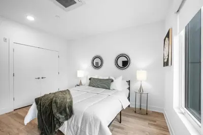 a white bedroom with a large bed and two mirrors at Bright 1BR Haven - Balcony Skyline Views in Philadelphia