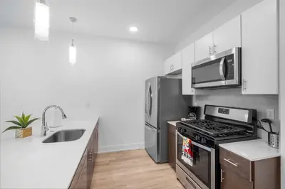 a kitchen with stainless steel appliances and a sink at Bright 1BR Haven - Balcony Skyline Views in Philadelphia