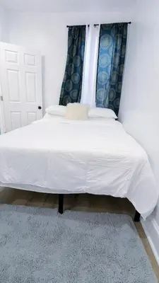 a bedroom with a bed with white sheets and a window at 3bedroom 2 bath minutes away from Temple, Philly museum, Philly zoo , center city in Philadelphia