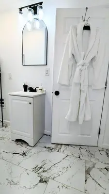 a white bathroom with a robe hanging on a door at 3bedroom 2 bath minutes away from Temple, Philly museum, Philly zoo , center city in Philadelphia