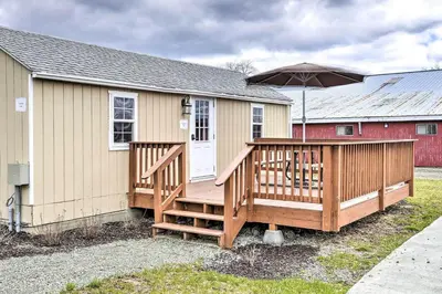 a house with a large deck with an umbrella at Log Cabin and Suite, Friendly Retreat Close to Skiing in Pleasant Mount