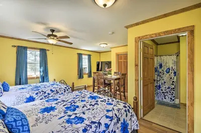 a bedroom with a blue and white bed and a dining room at Wander & Unwind, Log Cabin and Suites Close to Ski Mountain in Pleasant Mount