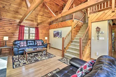 a living room with a couch and a staircase in a cabin at Wander & Unwind, Log Cabin and Suites Close to Ski Mountain in Pleasant Mount