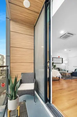 a room with a balcony with a chair and a bedroom at Stylish Studio - Pool, Gym & Balcony Bliss in Philadelphia
