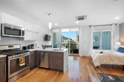 a kitchen with stainless steel appliances and a bedroom at Stylish Studio - Pool, Gym & Balcony Bliss in Philadelphia
