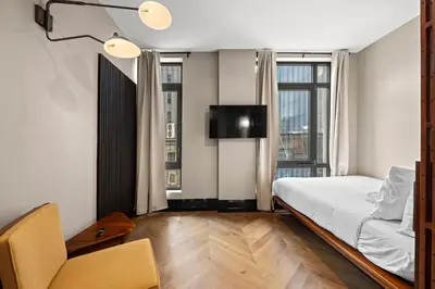 a bedroom with a bed and a tv and some windows at Freeman 401 by Rove Travel - Studio w Shared Amenities in New York