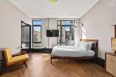 a bedroom with a bed and a chair and windows at Freeman 501 by Rove Travel - Studio with Shared Amenities in New York