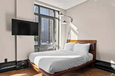 a bedroom with a bed with a flat screen tv at Freeman 501 by Rove Travel - Studio with Shared Amenities in New York