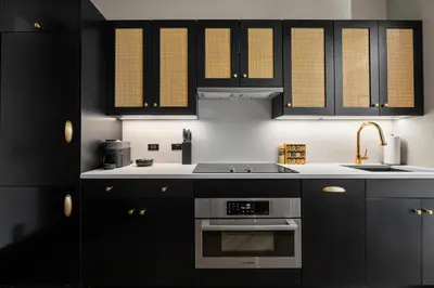 a kitchen with black cabinets and a sink at Freeman 801 by Rove Travel - Studio with Shared Amenities in New York