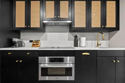 a kitchen with black cabinets and a stainless steel oven at Freeman 901 by Rove Travel - Studio with Shared Amenities in New York
