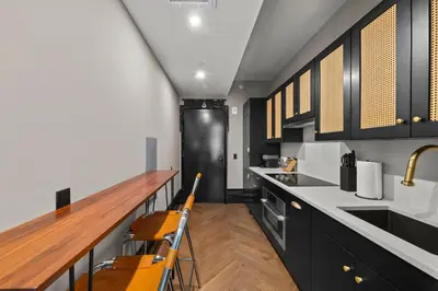 a kitchen with black cabinets and a wooden counter top at Freeman 901 by Rove Travel - Studio with Shared Amenities in New York