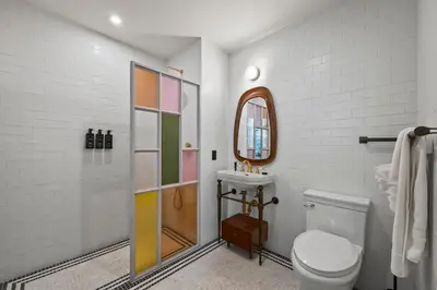 a bathroom with a toilet and a sink and a mirror at Freeman 901 by Rove Travel - Studio with Shared Amenities in New York