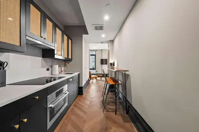 a kitchen with black and white cabinets and a table at Freeman 1001 by Rove Travel - Studio with Shared Amenities in New York