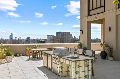 an outdoor kitchen on a patio with a view of the city at Freeman 1101 by Rove Travel - Studio with Shared Amenities in New York