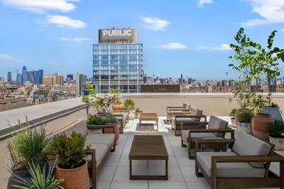 a rooftop patio with couches and tables and a building at Freeman 1201 by Rove Travel - Studio with Shared Amenities in New York