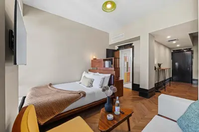 a bedroom with a bed and a living room at Freeman 1201 by Rove Travel - Studio with Shared Amenities in New York