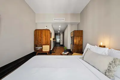 a bedroom with a white bed and a living room at Freeman 203 by Rove Travel -1BR Condo with Shared Amenities in New York