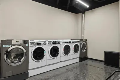 a laundry room with three washing machines in it at Freeman 403 by Rove Travel - 1BR Condo with Shared Amenities in New York